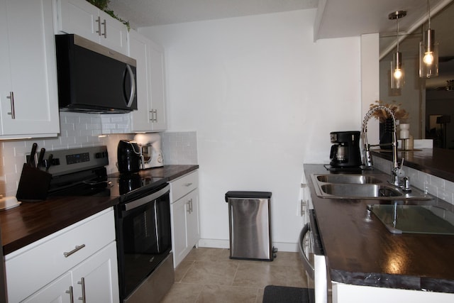 kitchen with wooden counters, a sink, backsplash, stainless steel appliances, and white cabinets
