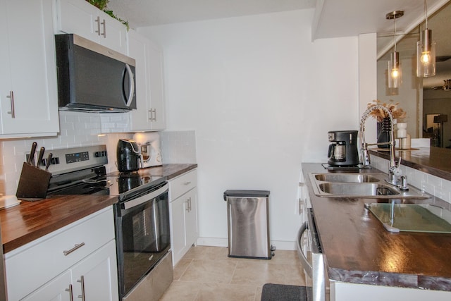 606 6th Way, West Palm Beach, FL 33407 - kitchen with stainless steel appliances, wooden counters, backsplash, and white cabinets