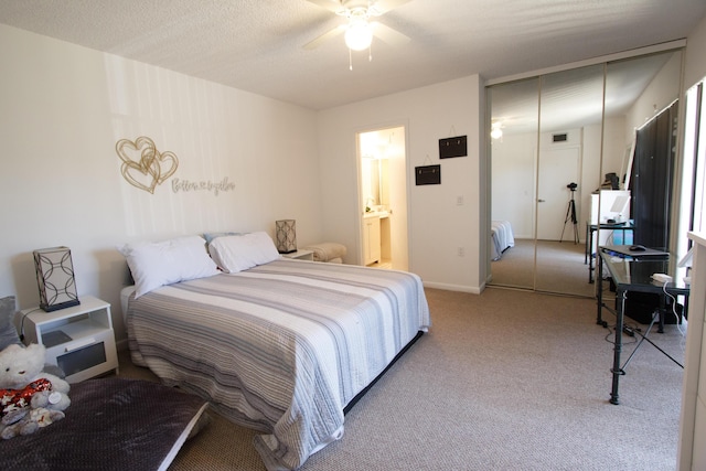 carpeted bedroom with ensuite bathroom and a ceiling fan