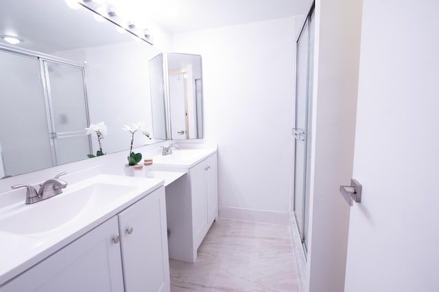 bathroom featuring a sink, two vanities, a shower stall, and marble finish floor
