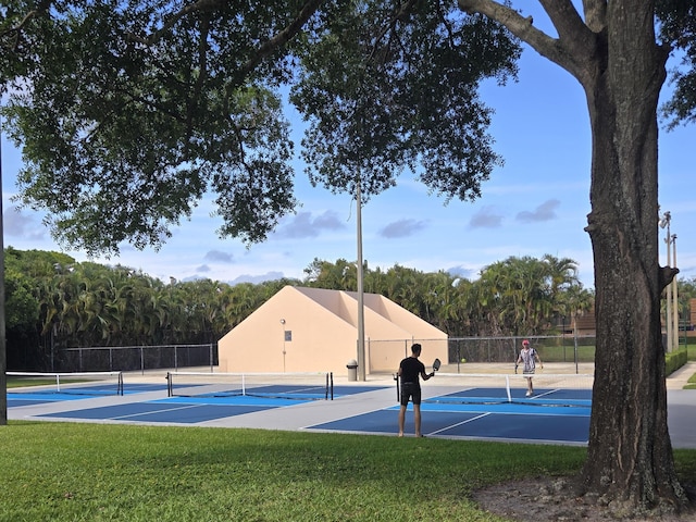 view of tennis court with a lawn, fence, and community basketball court