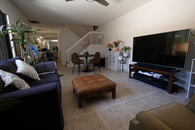 tiled living area with stairway, visible vents, a textured ceiling, and ceiling fan with notable chandelier