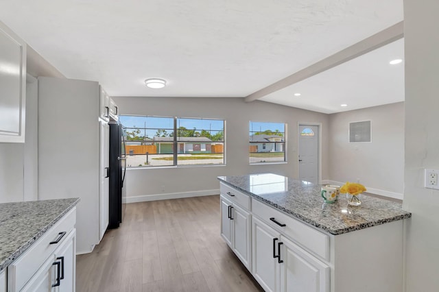 kitchen featuring light wood-type flooring, white cabinetry, freestanding refrigerator, baseboards, and light stone countertops