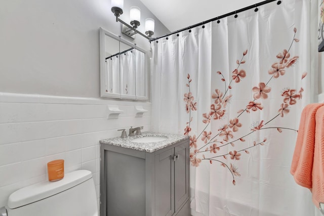 full bath with vanity, toilet, tile walls, wainscoting, and a shower with curtain