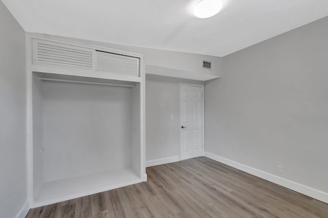 unfurnished bedroom with wood finished floors, baseboards, and a closet