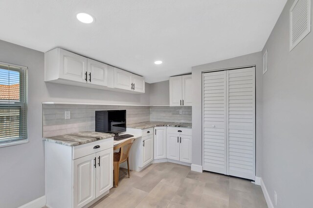 kitchen with backsplash, light stone countertops, white cabinetry, baseboards, and recessed lighting