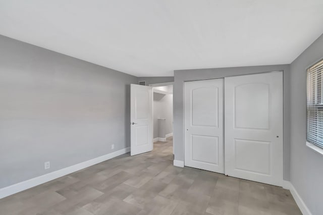 unfurnished bedroom with a closet, baseboards, and light wood finished floors