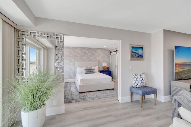 bedroom with baseboards, a barn door, and light wood-style floors