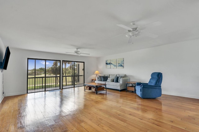 living area featuring a ceiling fan, light wood-type flooring, and baseboards
