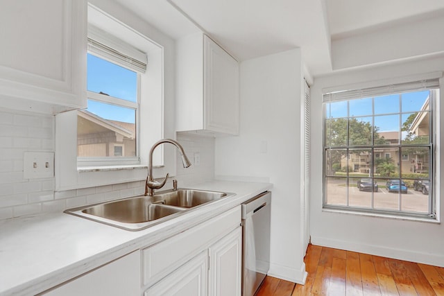 kitchen with a sink, dishwasher, backsplash, and light countertops