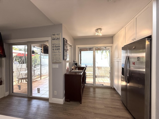 kitchen featuring stainless steel refrigerator with ice dispenser, white cabinetry, dark wood-type flooring, baseboards, and plenty of natural light