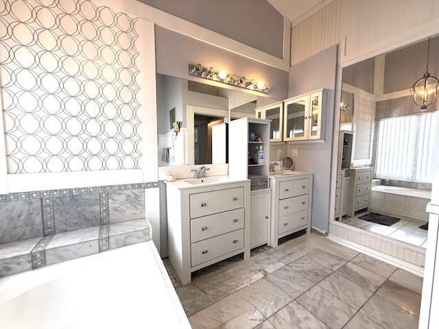 full bathroom with marble look tile flooring, a garden tub, vanity, and a chandelier
