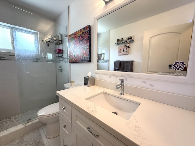 bathroom with toilet, a tile shower, and vanity