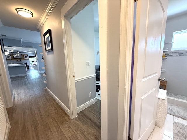 hallway featuring wood finished floors, crown molding, and baseboards
