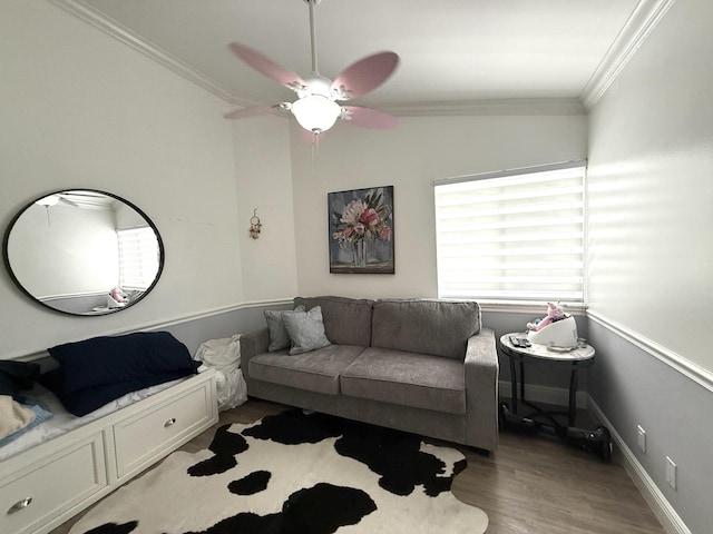 living area featuring wood finished floors, ornamental molding, ceiling fan, and baseboards