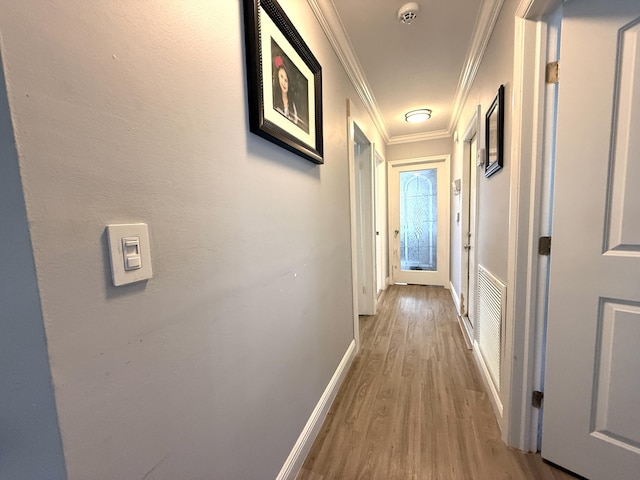 corridor with ornamental molding, wood finished floors, and baseboards