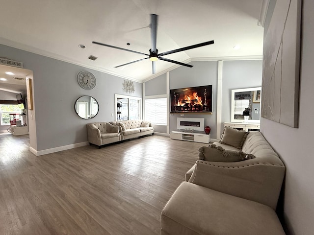 living area featuring wood finished floors, a ceiling fan, baseboards, lofted ceiling, and ornamental molding