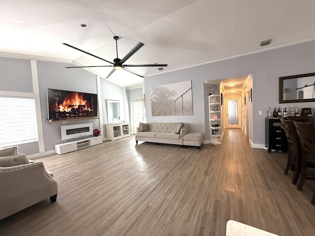 living room with crown molding, wood finished floors, ceiling fan, lofted ceiling, and baseboards