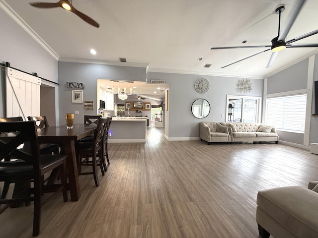 living area featuring a ceiling fan, a barn door, crown molding, lofted ceiling, and baseboards