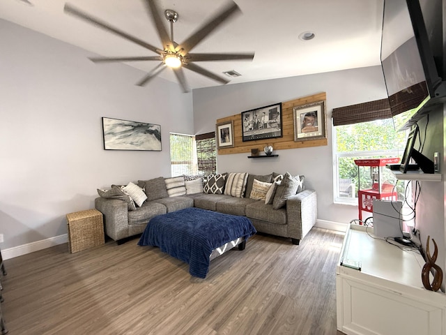 living area with ceiling fan, baseboards, light wood-style flooring, and vaulted ceiling