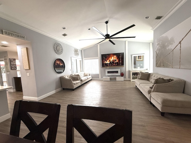 living area featuring ceiling fan, wood finished floors, crown molding, baseboards, and vaulted ceiling