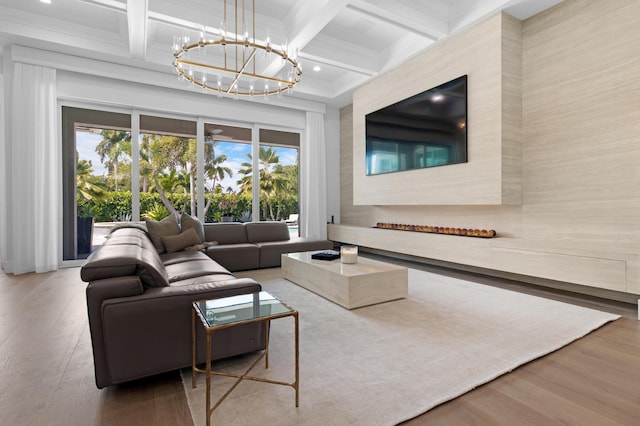 living area with beam ceiling, a chandelier, wood finished floors, coffered ceiling, and crown molding