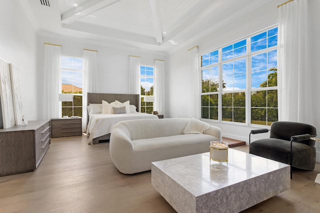 bedroom with a tray ceiling, crown molding, and light wood finished floors