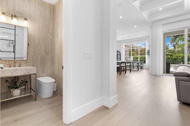 hall featuring wood finished floors, a sink, coffered ceiling, recessed lighting, and ornamental molding