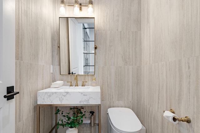 half bath with tile walls, toilet, and vanity