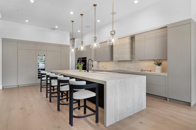 kitchen with modern cabinets, light countertops, a spacious island, gray cabinetry, and decorative backsplash