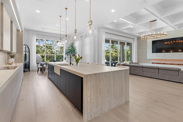 kitchen featuring modern cabinets, a sink, light wood-style flooring, light countertops, and beam ceiling