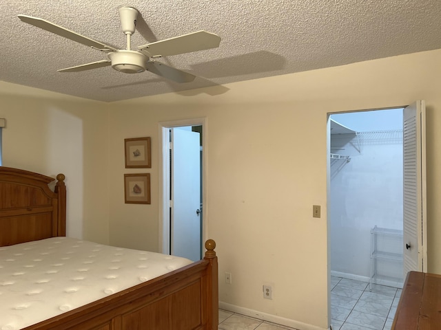 bedroom featuring a textured ceiling, a ceiling fan, a spacious closet, a closet, and baseboards