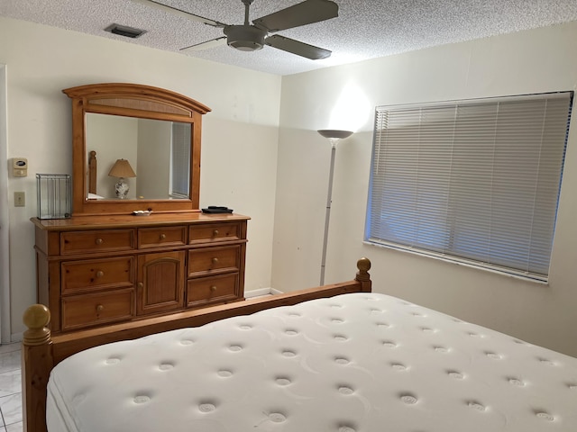 bedroom with a textured ceiling, ceiling fan, and light tile patterned flooring