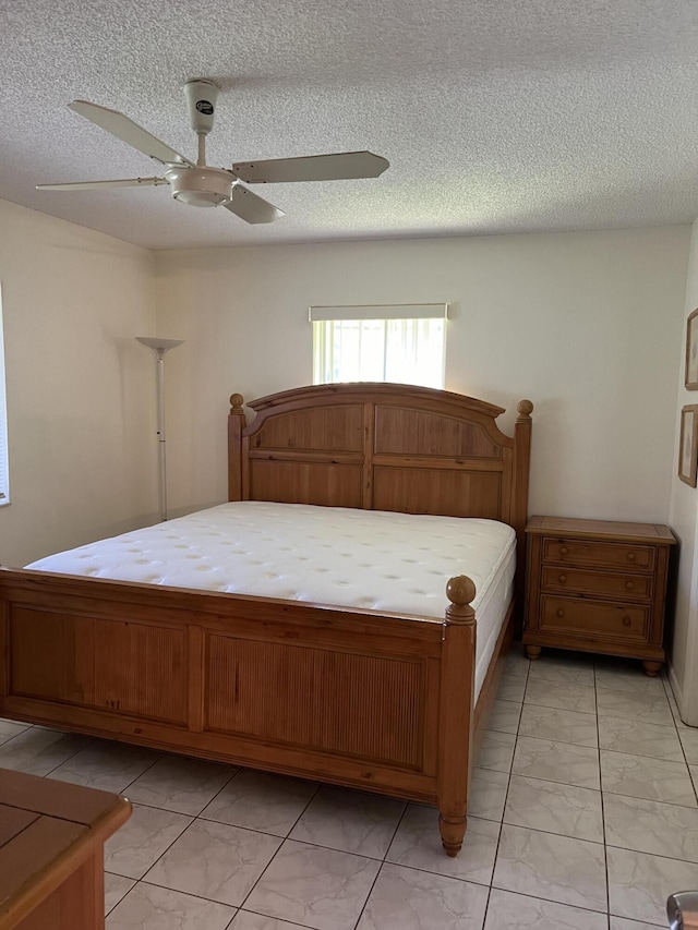 bedroom featuring light marble finish flooring, a ceiling fan, and a textured ceiling