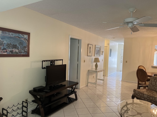 living room with a ceiling fan, light tile patterned floors, a textured ceiling, and baseboards