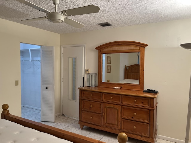 bedroom with light tile patterned floors, a textured ceiling, ceiling fan, and baseboards