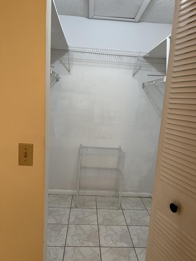 walk in closet featuring marble look tiles