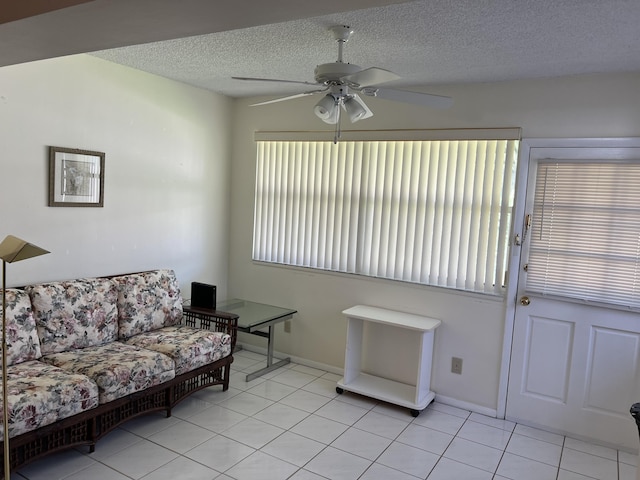 living room featuring a ceiling fan, light tile patterned floors, a textured ceiling, and baseboards