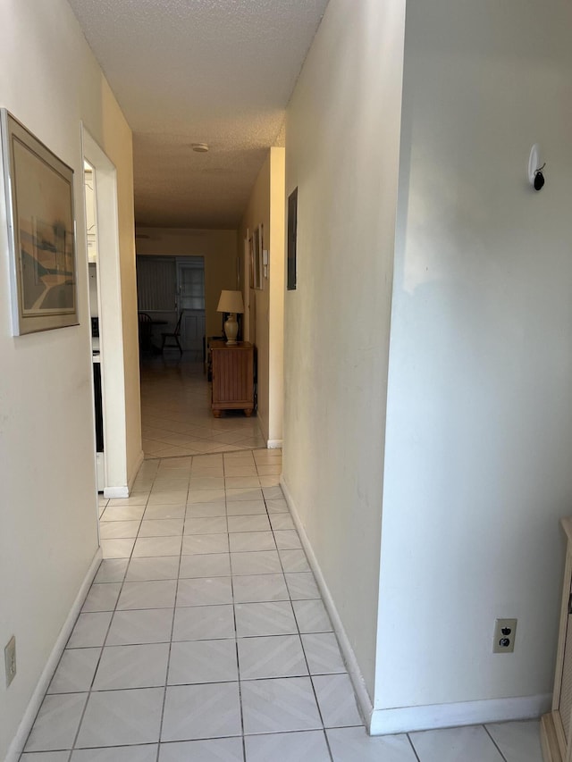 hallway with light tile patterned floors and baseboards