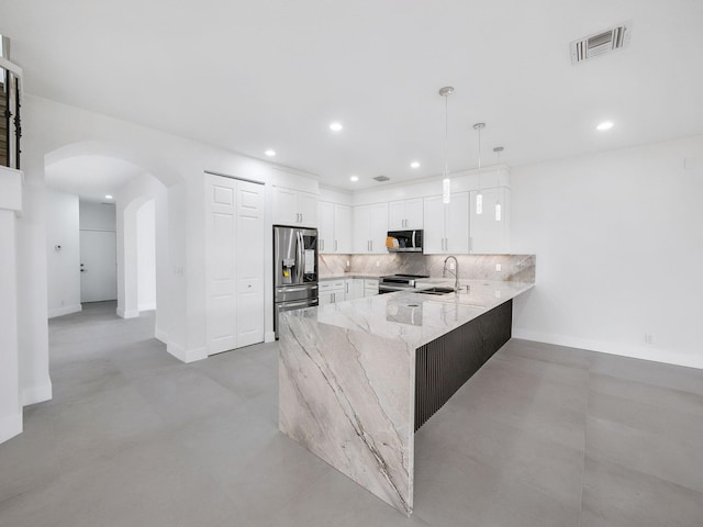 7285 Via Luria, Lake Worth, FL 33467 - kitchen with a peninsula, stainless steel appliances, visible vents, arched walkways, and light stone countertops