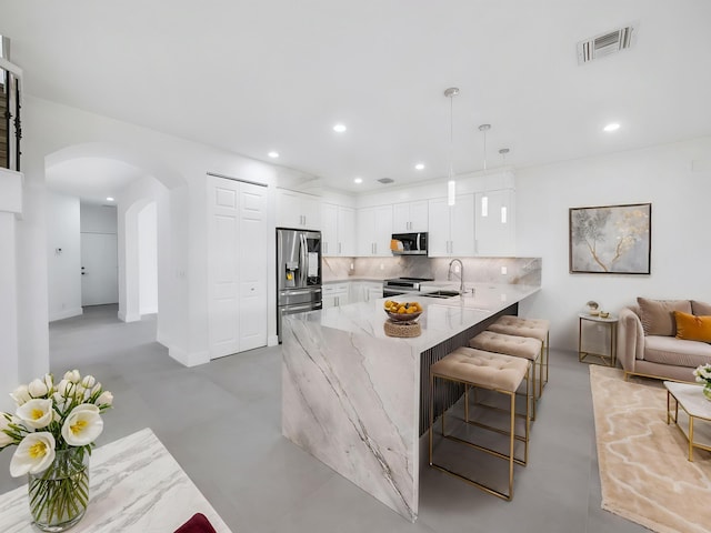 7285 Via Luria, Lake Worth, FL 33467 - kitchen with a peninsula, visible vents, arched walkways, appliances with stainless steel finishes, and light stone counters