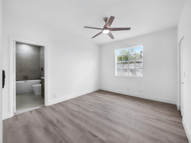 7285 Via Luria, Lake Worth, FL 33467 - unfurnished bedroom featuring ensuite bath, baseboards, a ceiling fan, and wood finished floors
