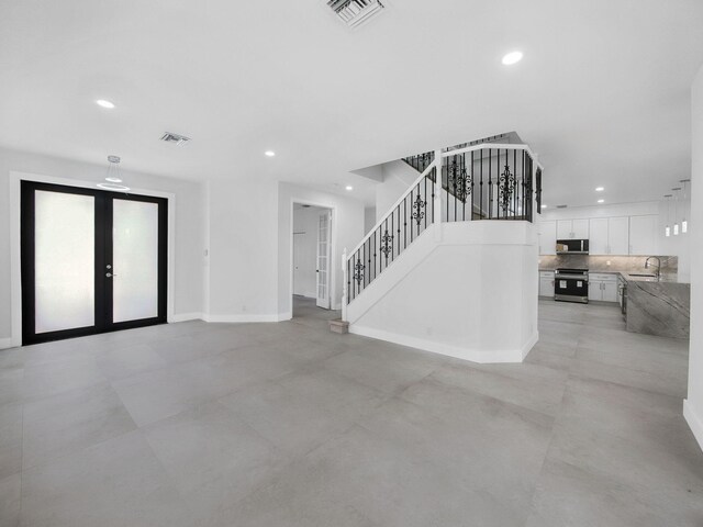 7285 Via Luria, Lake Worth, FL 33467 - unfurnished living room featuring french doors, a sink, stairs, visible vents, and recessed lighting