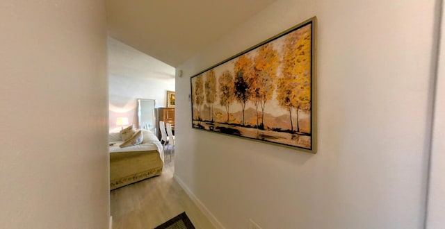 hall with lofted ceiling, baseboards, and wood finished floors