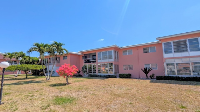 rear view of house featuring a yard and stucco siding