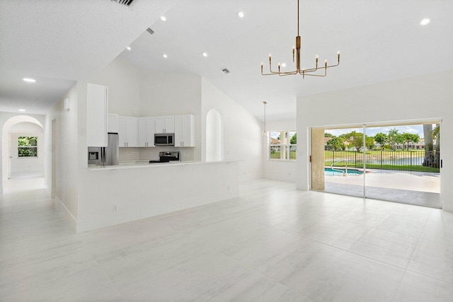 unfurnished living room with high vaulted ceiling, arched walkways, a chandelier, recessed lighting, and baseboards