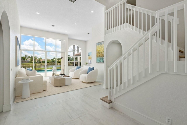 living area featuring stairway, arched walkways, recessed lighting, tile patterned flooring, and baseboards