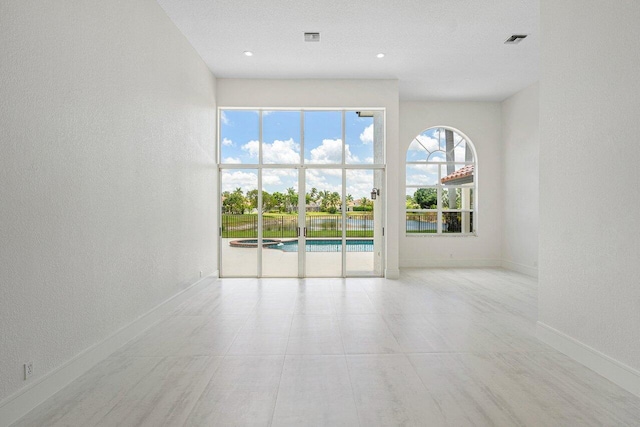 empty room featuring baseboards, a textured wall, and recessed lighting