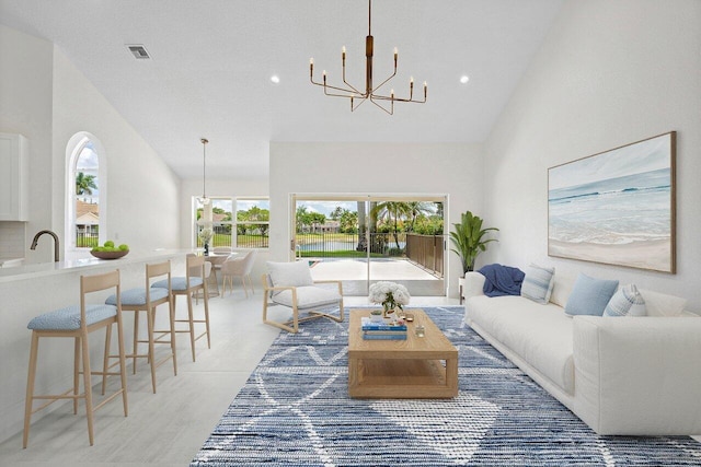 living room featuring a chandelier, high vaulted ceiling, recessed lighting, and a water view