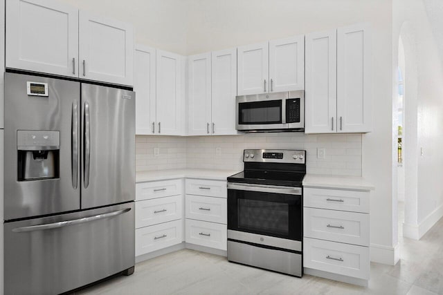 kitchen with stainless steel appliances, light countertops, tasteful backsplash, and white cabinets